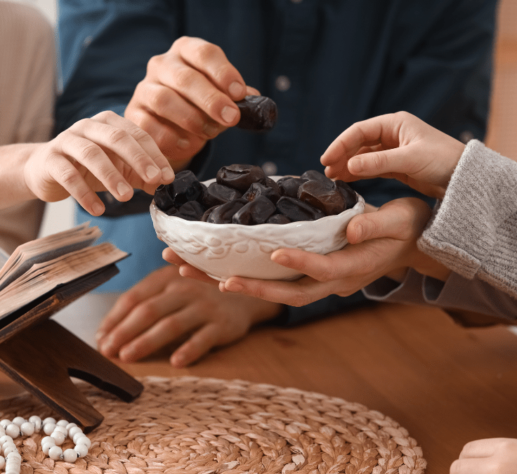 Plato con dátiles y manos tomándolos para romper el ayuno en Ramadán