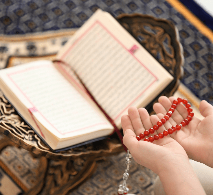 Manos con un tasbih junto a un Qurán abierto mientras se recitan ṣalawāt