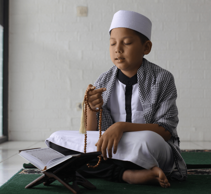 Niño arrodillado realizando dhikr y pronunciando Subḥān Allāh wa bi-ḥamdih
