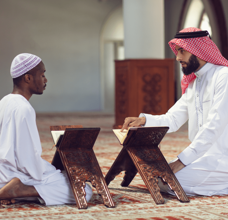 Dos hombres en una mezquita, uno levantando el dedo índice realizando la Shahada