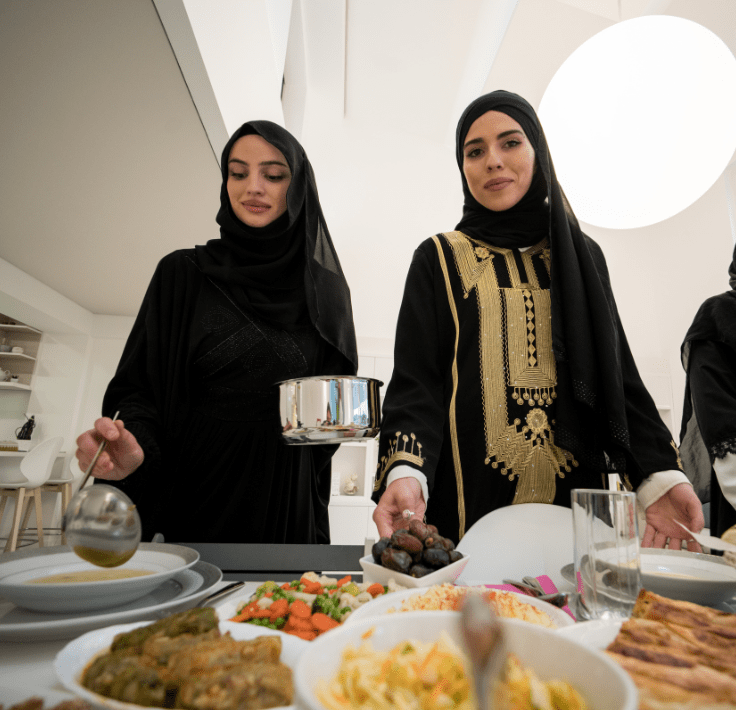 Dos mujeres musulmanas preparando y sirviendo comida para el rompimiento del ayuno en Ramadán