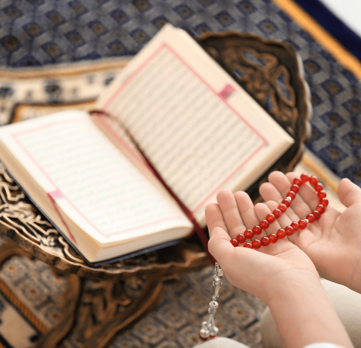 Manos con un tasbih junto a un Qurán abierto mientras se recitan ṣalawāt