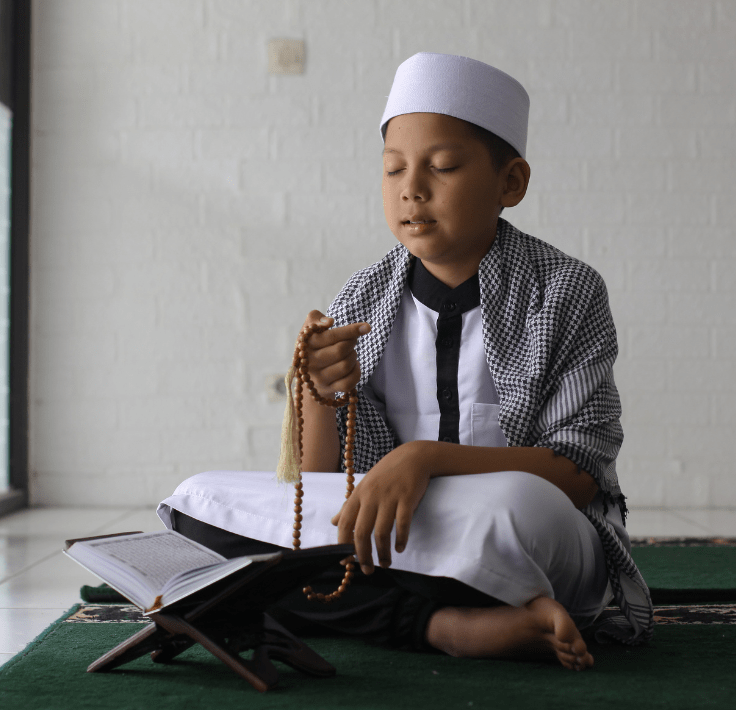 Niño arrodillado realizando dhikr y pronunciando Subḥān Allāh wa bi-ḥamdih