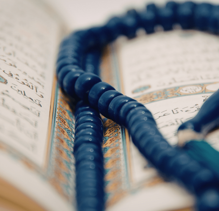 Tasbih colocado dentro de un Qurán abierto representando el dhikr
